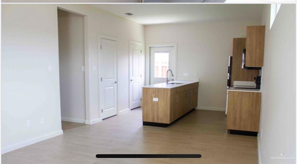 3600 Jessica Lane, Unit 2 Weslaco, TX 78599 - Photo 3 of 7 Kitchen featuring a peninsula, a sink, light countertops, light wood-type flooring, and baseboards