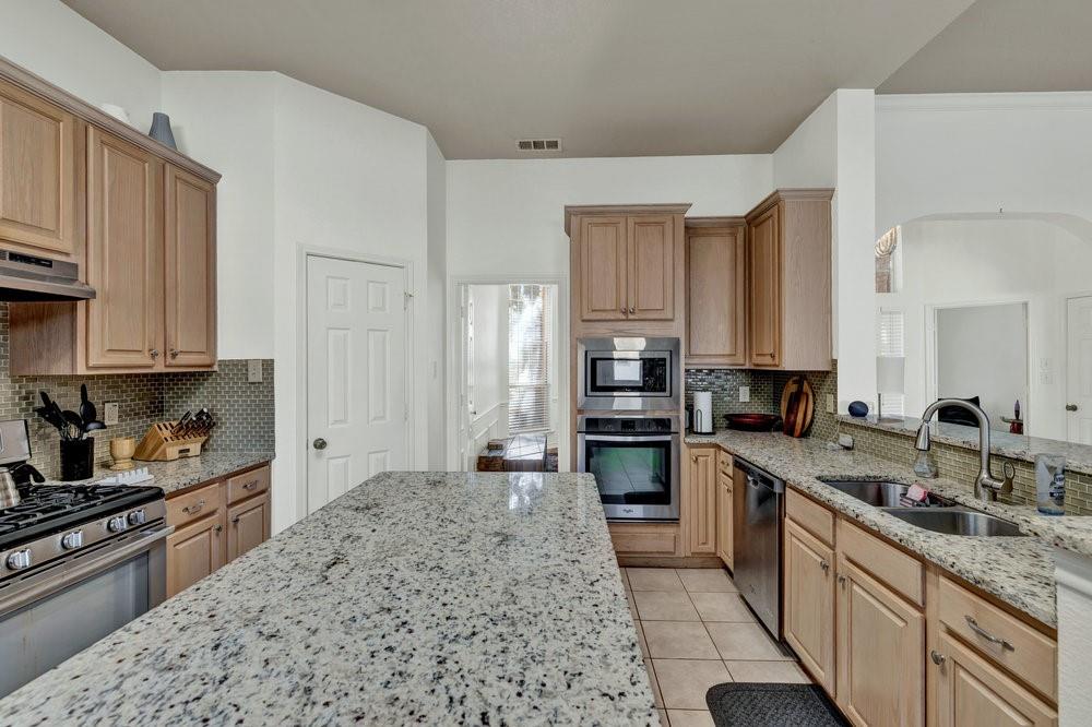 18 Equestrian Court Mansfield, TX 76063 - Photo 8 of 28 a kitchen with stainless steel appliances granite countertop a sink stove refrigerator and cabinets