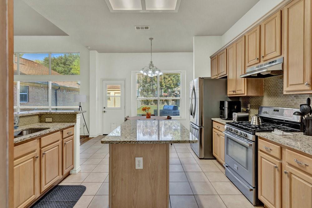 18 Equestrian Court Mansfield, TX 76063 - Photo 9 of 28 a large kitchen with granite countertop a stove refrigerator and cabinets