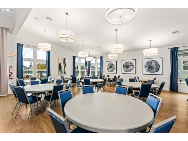 a kitchen with stainless steel appliances kitchen island granite countertop a refrigerator a stove a sink a dining table and chairs with wooden floor