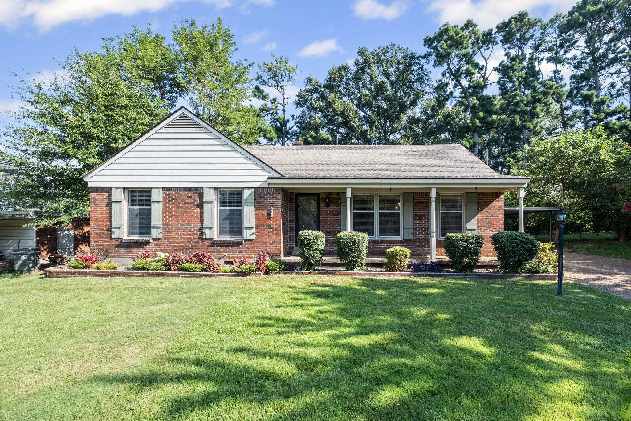 a front view of a house with a garden and trees