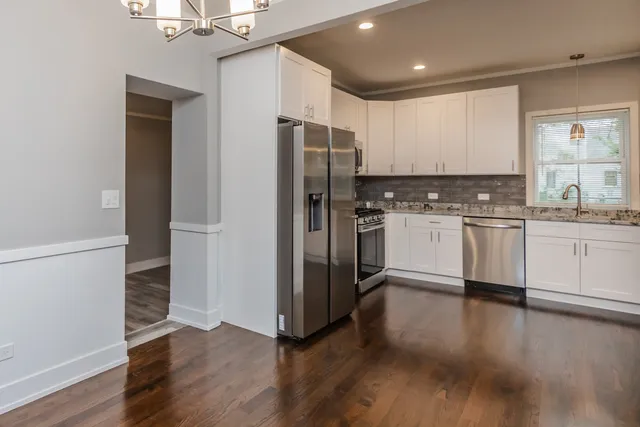 a kitchen with stainless steel appliances a sink cabinets and wooden floor