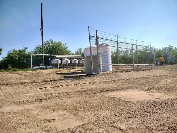 a view of a dry yard with wooden fence