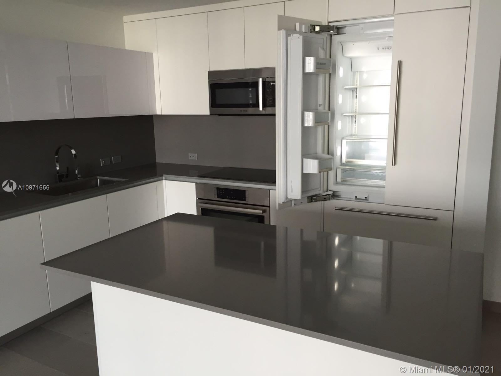 68 Southeast 6th Street, Unit 1010 Miami, FL 33131 - Photo 38 of 43 a kitchen with a sink and wooden cabinets