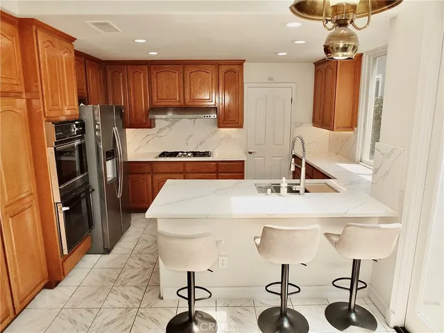 a kitchen with stainless steel appliances granite countertop a refrigerator sink and white cabinets