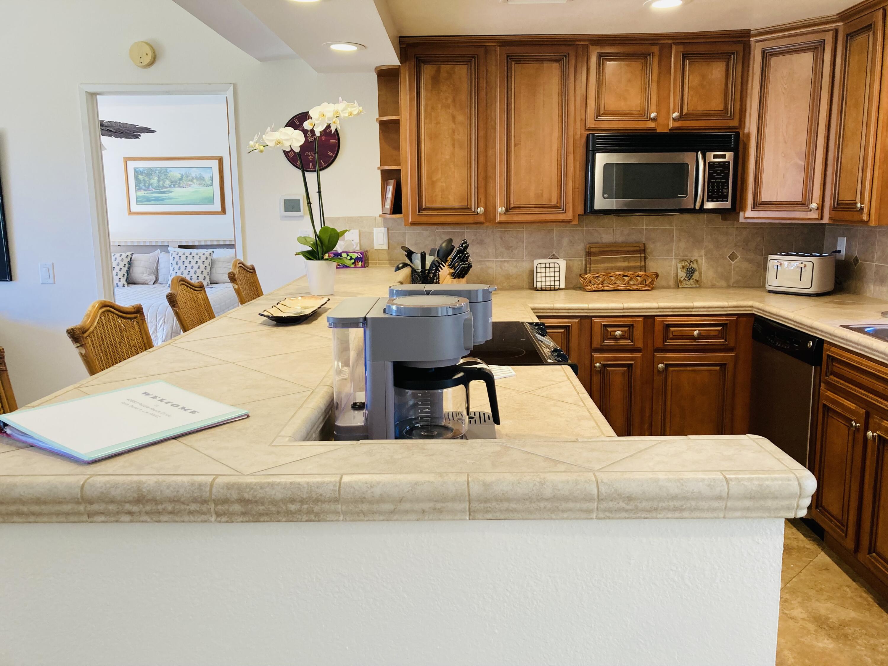 40553 Pebble Beach Circle Palm Desert, CA 92211 - Photo 19 of 22 a kitchen with kitchen island granite countertop wooden cabinets a stove top oven a sink and dishwasher