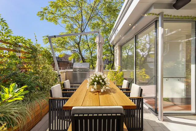 a view of a patio with table and chairs and floor to ceiling window next to a yard