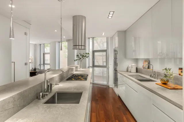 a large kitchen with stainless steel appliances kitchen island granite countertop a refrigerator a sink a stove and white cabinets with wooden floor