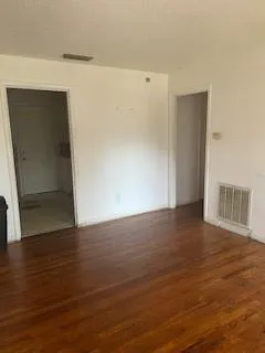 a view of an empty room with wooden floor and closet