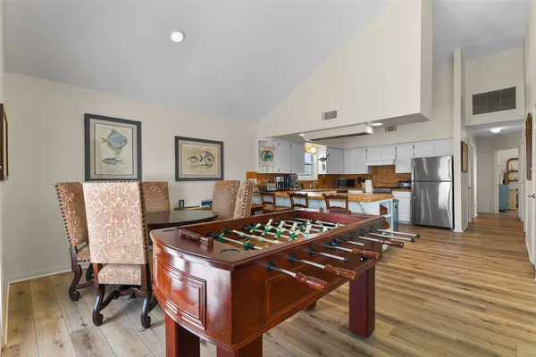 a kitchen with a table chairs refrigerator and wooden floor