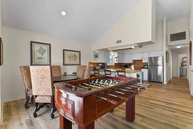 a kitchen with a table chairs refrigerator and wooden floor