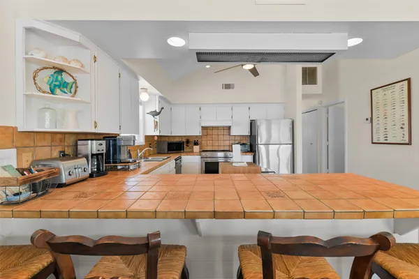 a large kitchen with stainless steel appliances kitchen island granite countertop a table chairs and a refrigerator