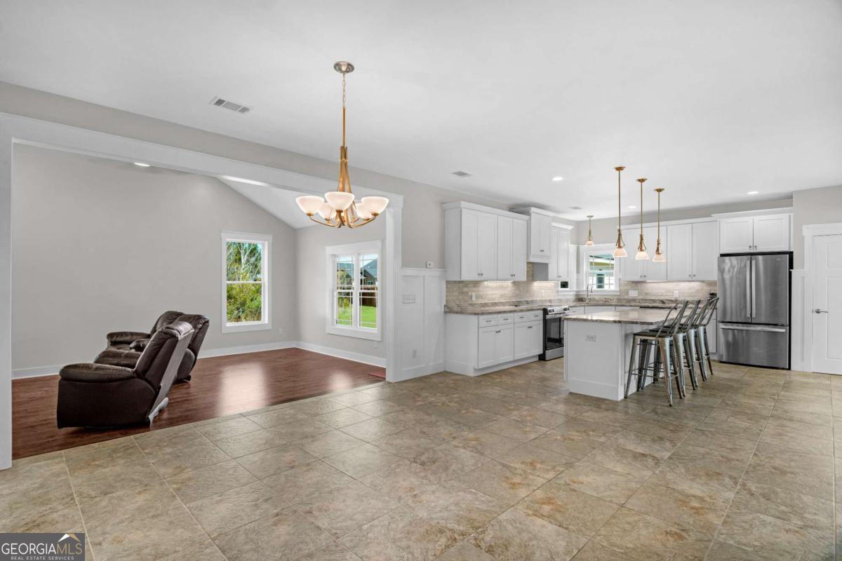 328 Windsor Road Guyton, GA 31312 - Photo 19 of 39 a open kitchen with stainless steel appliances kitchen island granite countertop a table chairs and a sink