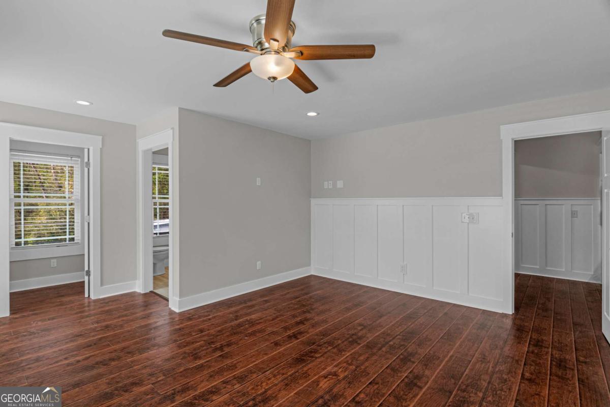328 Windsor Road Guyton, GA 31312 - Photo 21 of 39 an empty room with wooden floor chandelier fan and windows