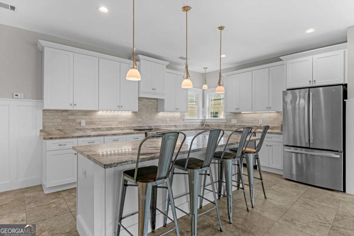 328 Windsor Road Guyton, GA 31312 - Photo 6 of 39 a kitchen with stainless steel appliances granite countertop a table chairs stove and refrigerator