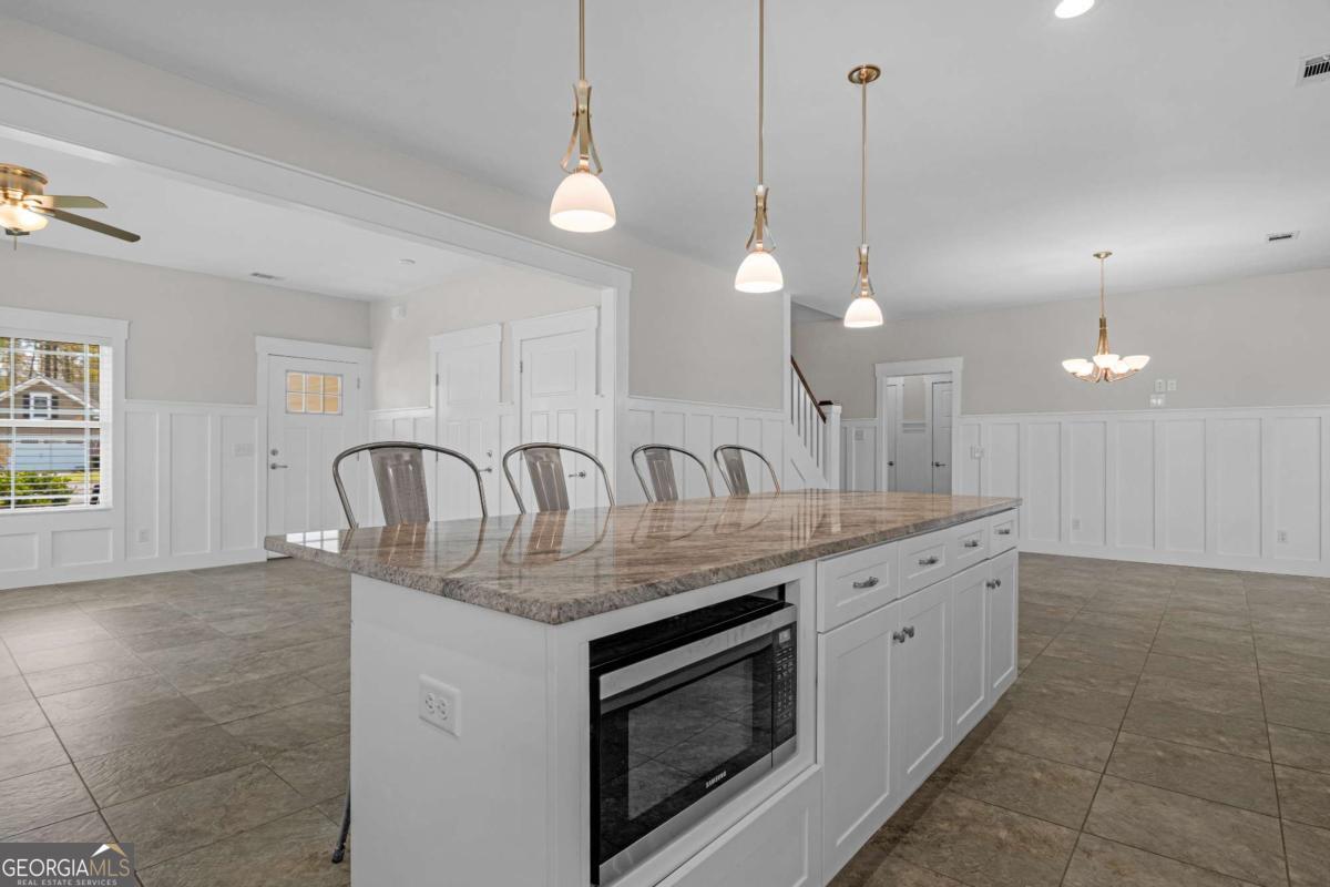 328 Windsor Road Guyton, GA 31312 - Photo 8 of 39 a kitchen with granite countertop a stove a sink a dining table and chairs