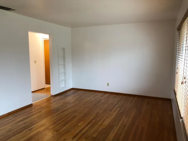 an empty room with wooden floor and window