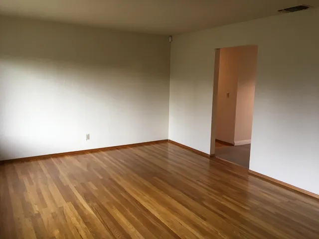 a view of an empty room with wooden floor