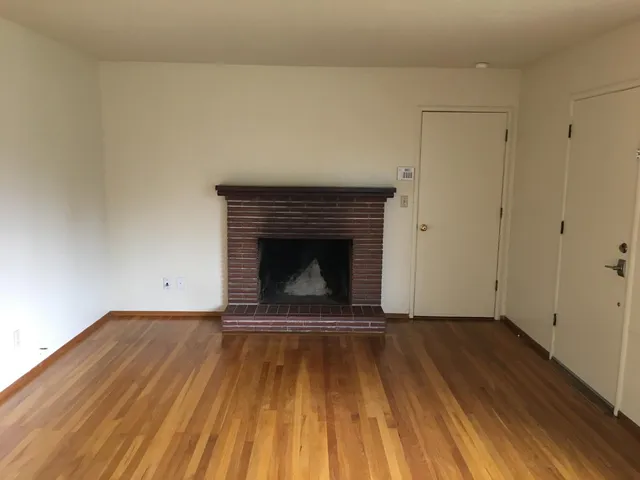 a view of a livingroom with wooden floor and a fireplace