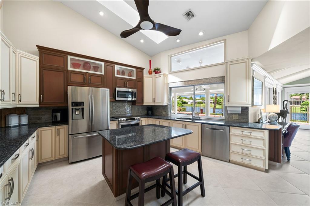 547 Devils Lane Naples, FL 34103 - Photo 6 of 13 a kitchen with stainless steel appliances granite countertop a stove refrigerator sink and cabinets