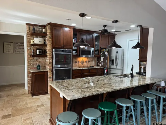 a kitchen with granite countertop a table chairs stainless steel appliances and cabinets
