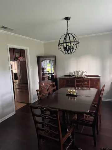 a dining room with wooden floor a chandelier a wooden table and chairs