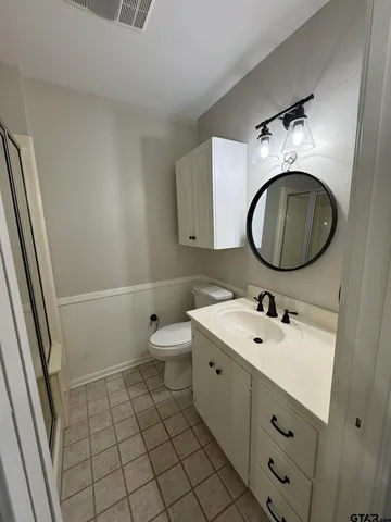 a bathroom with a toilet sink vanity granite and a mirror