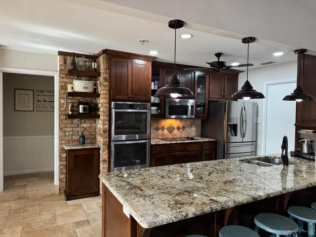 a kitchen with stainless steel appliances kitchen island granite countertop a refrigerator a stove and a sink