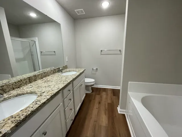 a bathroom with a granite countertop sink a toilet and bathtub