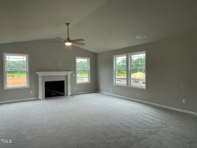 an empty room with windows and fireplace