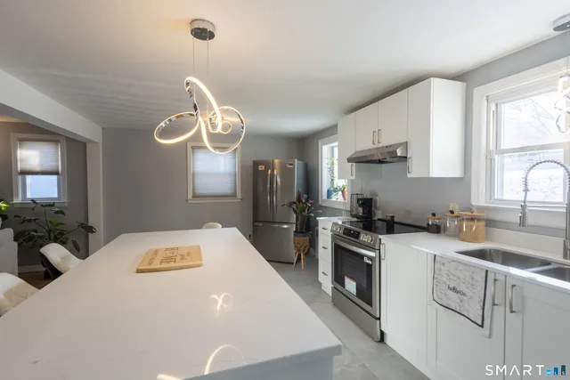 a kitchen that has a lot of white cabinets and stainless steel appliances
