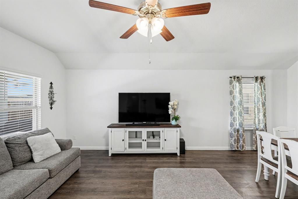 706 Spur Ridge Princeton, TX 75407 - Photo 15 of 36 Living area with dark wood-style floors, vaulted ceiling, healthy amount of natural light, and a ceiling fan