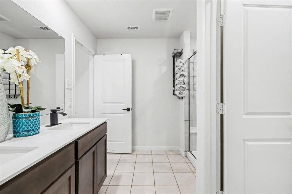 706 Spur Ridge Princeton, TX 75407 - Photo 22 of 36 Bathroom with a stall shower, double vanity, and light tile patterned flooring