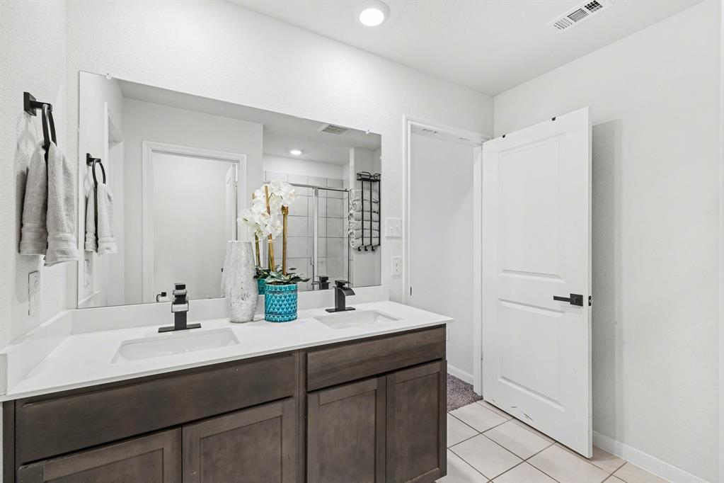 706 Spur Ridge Princeton, TX 75407 - Photo 23 of 36 Bathroom featuring double vanity, a shower stall, and light tile patterned flooring