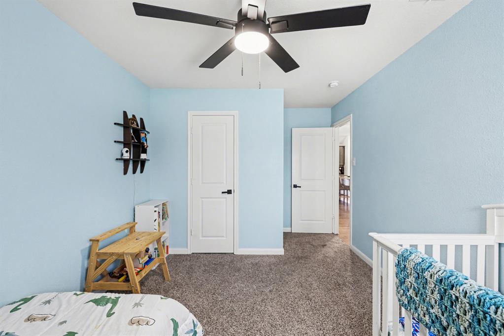 706 Spur Ridge Princeton, TX 75407 - Photo 25 of 36 Bedroom featuring a nursery area, dark carpet, and ceiling fan