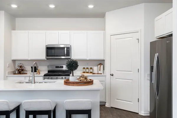 a kitchen with stainless steel appliances a dining table chairs microwave and refrigerator