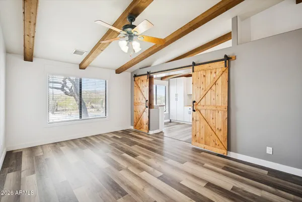 a view of empty room with wooden floor and fan