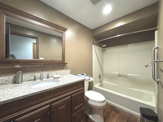 a bathroom with a granite countertop sink a toilet a mirror and bathtub