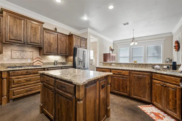 a kitchen with kitchen island granite countertop a sink stove and refrigerator