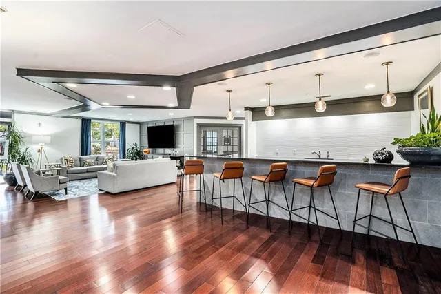 a living room with furniture kitchen view and a wooden floor
