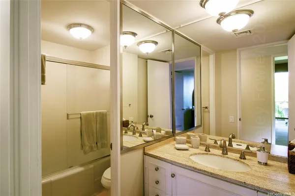 a bathroom with a granite countertop sink mirror and a bathtub