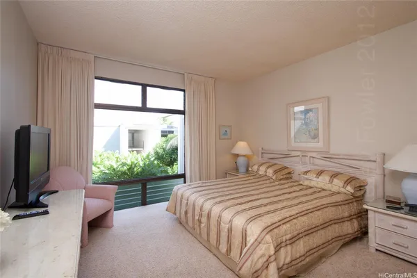 a bedroom with a bed and a flat tv screen on dresser