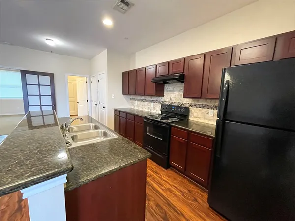 a kitchen with stainless steel appliances granite countertop a refrigerator a stove a sink and a microwave