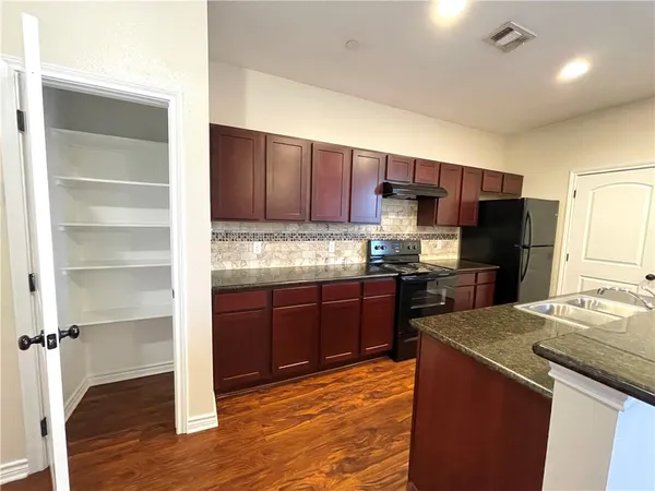 a kitchen with granite countertop wooden cabinets and stainless steel appliances
