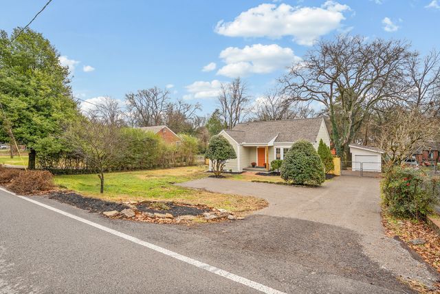 a view of a house with a yard and large trees