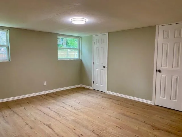 a view of an empty room with wooden floor and a window