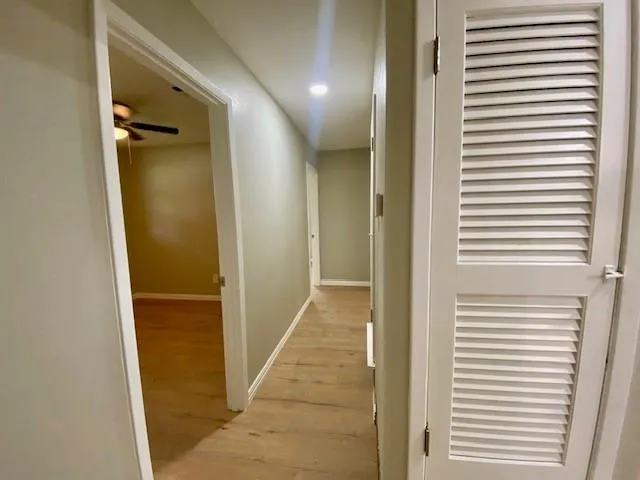 a view of a hallway with a door and a bathroom