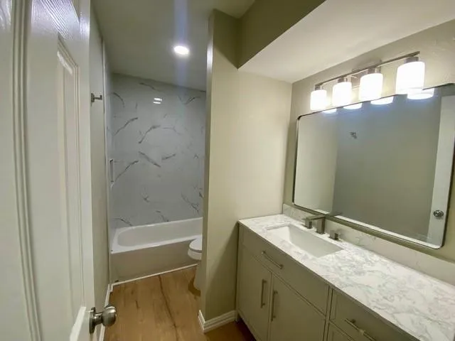 a bathroom with a granite countertop sink mirror and a bathtub