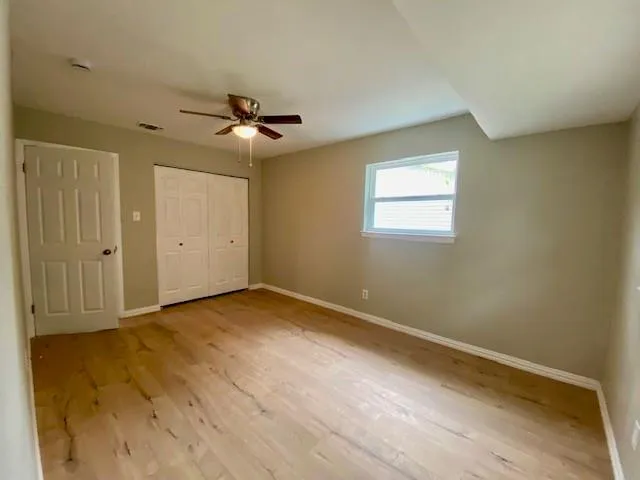 an empty room with windows and fan