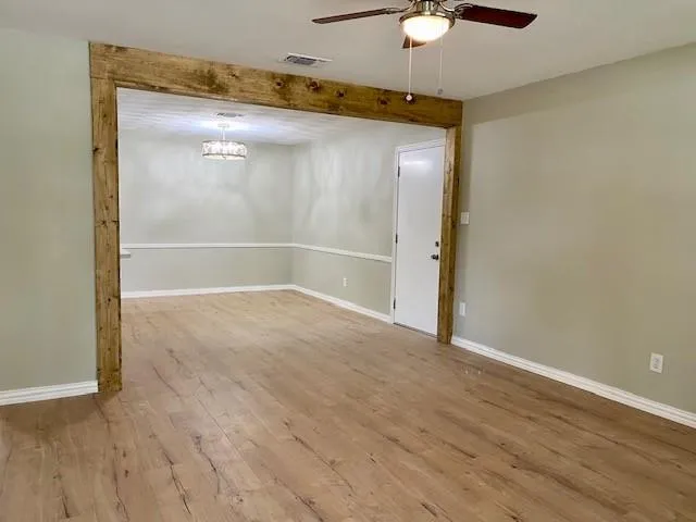 an empty room with wooden floor fan and windows